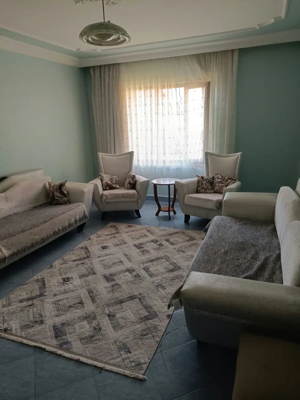 Armchairs by the window and a rug in the sunlit salon
