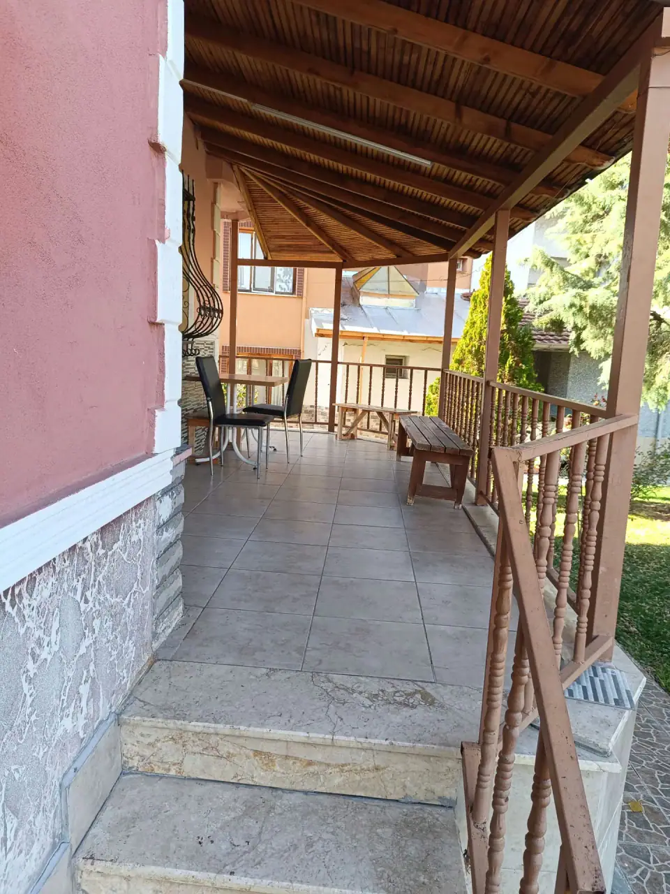 Ahşap çatılı terasta masa, sandalyeler ve bahçeye bakan korkuluk